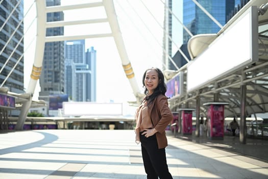 Confident mature businesswoman posing in modern cityscape.