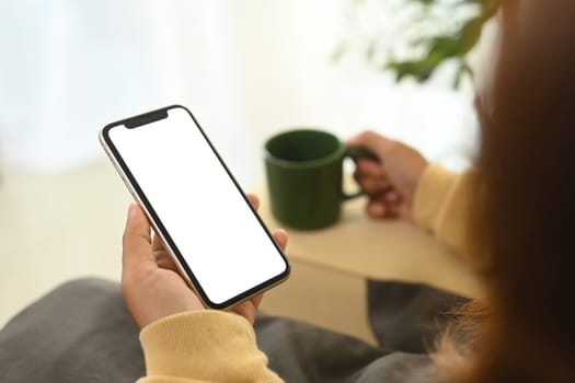 Close up of woman relaxing and holding smartphone with blank display.