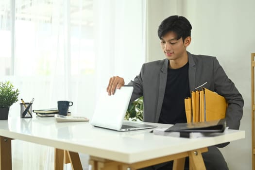 Young entrepreneur carrying archives and using laptop at office.