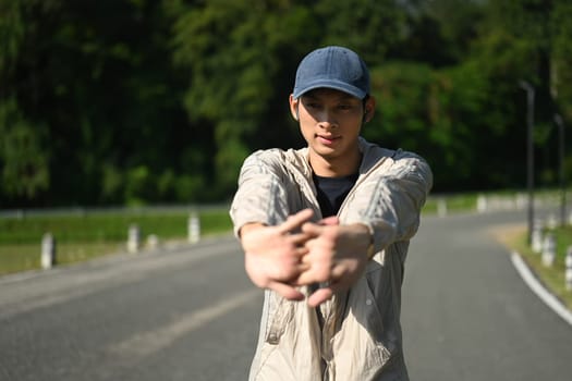 Portrait of sporty man stretching his arms preparing for morning workout.