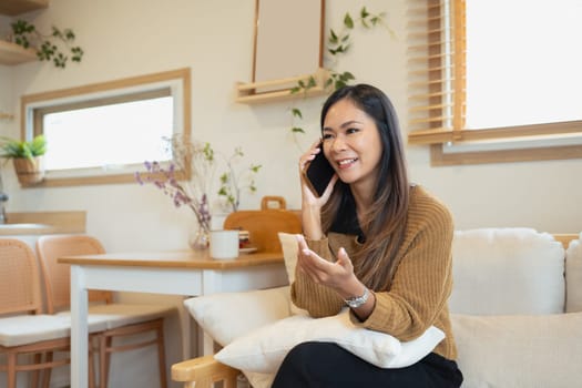 Attractive millennial woman having phone conversation in living room.