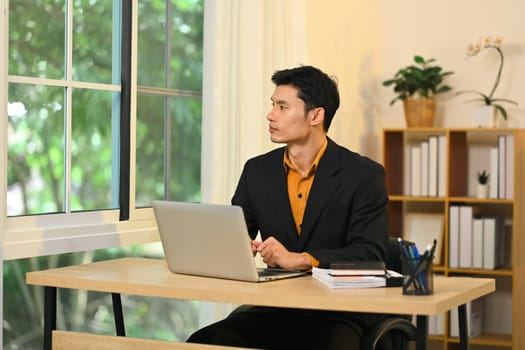 Thoughtful businessman looking out the window contemplating new ideas in office.