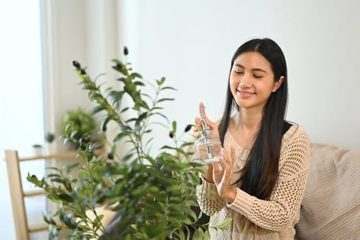 Charming young woman watering her indoor plant.
