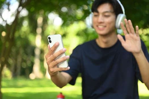 Smiling young sports man resting after training outdoors and using mobile phone.