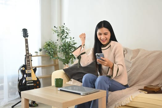 Surprised young pretty woman looking at mobile phone in excitement.
