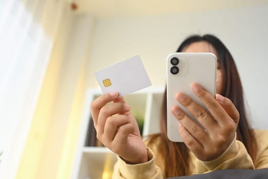 Cropped short happy young woman making online transaction at home with mobile application.