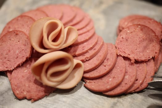 An elegantly artistic arrangement of various deli meats with decorative folds, perfect for fancy charcuterie boards