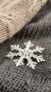 A detailed silver snowflake brooch resting on cozy woolen fabric, embodying winter elegance and warmth.