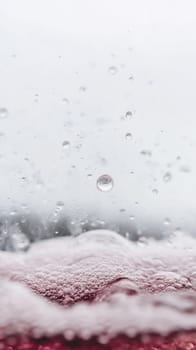 Raindrops fall onto a surface of red bubbling liquid, creating an intriguing mix of movement and detail.