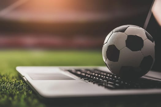 Soccer ball on laptop, sports betting concept in stadium setting.