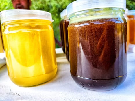 Various jars of honey showcase different colors and textures, capturing the richness of natural sweetness in a market setting.