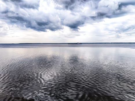 A vast expanse of water stretches out beneath a cloudy sky that fills the background, creating a serene yet dramatic atmosphere