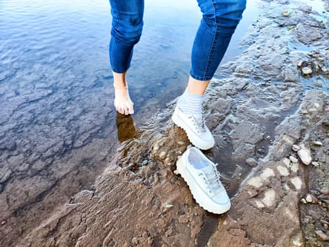 Footsteps in shallow water and shoes resting on dry ground as someone enjoys refreshing moment by the river on a sunny day
