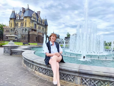 A woman enjoys her travel adventure at Garibaldi Castle, showcasing her excitement in a historic setting. The adventures of a middle-aged female tourist on a trip