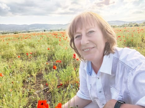 A happy girl in a poppy field. The journey of a middle-aged woman in summer. A tourist on trip