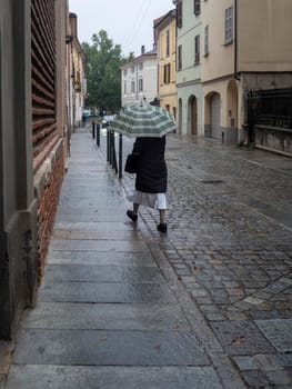 Cremona, Lombardy, Italy October 15th 2024 A serene nun walks alone in the rain with an umbrella in an old italian town, reflecting a calm and spiritual atmosphere