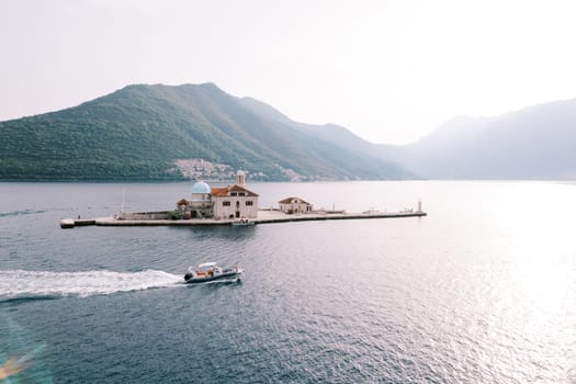Motorboat sails along the sea past the island of Gospa od Skrpjela. Montenegro. Drone. High quality photo