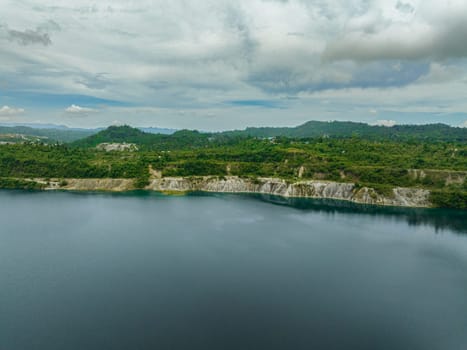 Aerial drone of mining quarry with flooded bottom. Lake with blue water near sand pit. Sipalay, Negros, Philippines.