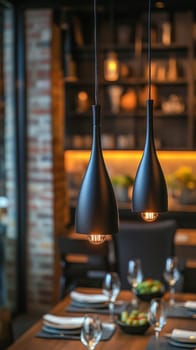 Two elegant black lamps hanging over a set dining table, creating a warm and inviting atmosphere in a modern restaurant