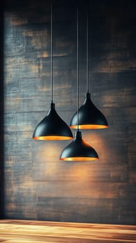 Three black and gold lamps hanging from the ceiling, illuminating a wooden table and a dark wall