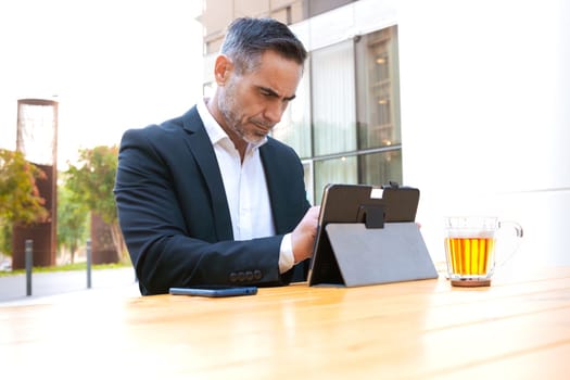 Business on the move: Businessman working on his digital tablet on the street. Man Hands Type On His Laptop Outdoors