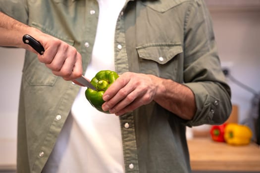 A close-up of a person slicing a fresh green bell pepper with a knife. The image highlights precision and care in food preparation, showcasing vibrant colors and the freshness of the vegetable