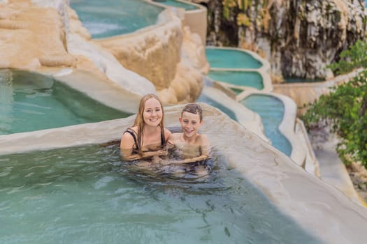 Mother with her toddler and teenage sons bathing in the hot springs of Grutas Tolantongo, Mexico. Family adventure, relaxation, and natural wellness concept.