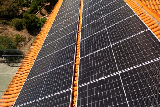 Drone capturing solar panels on house rooftop in city. Residential structure is equipped with green renewable energy generators.