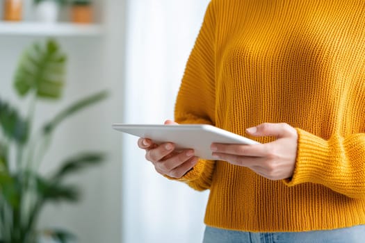 Engaged individual holding tablet in cozy indoor setting.