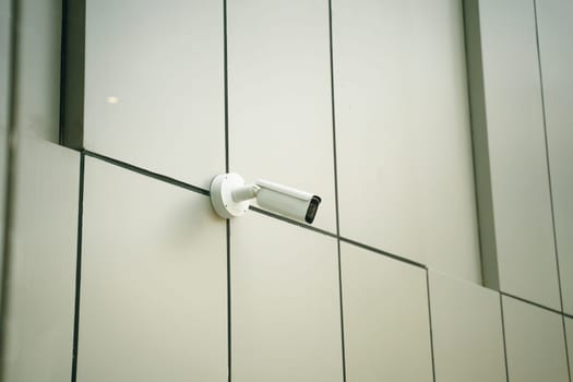 A sleek, modern surveillance camera has been installed on the exterior facade of a contemporary building design