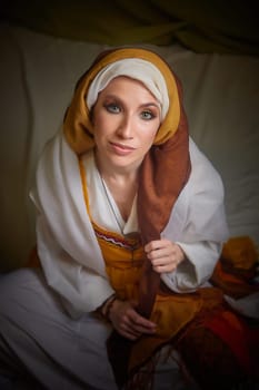 A girl dressed in stylized national clothing of eastern cultures poses elegantly, embodying the character of Rebekah from the Christian Bible.