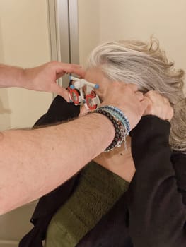 Cremona, Lombardy, Italy October 15th 2024 Optometrist using phoropter during eye examination of senior woman for vision correction and eye health