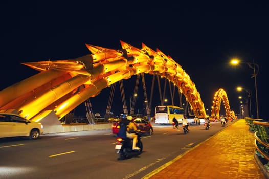 Motorcycle traffic on the Dragon Bridge over the Han River in Da Nang, Vietnam at night