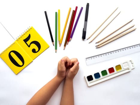 Creative workspace with art supplies and yellow calendar on white background.