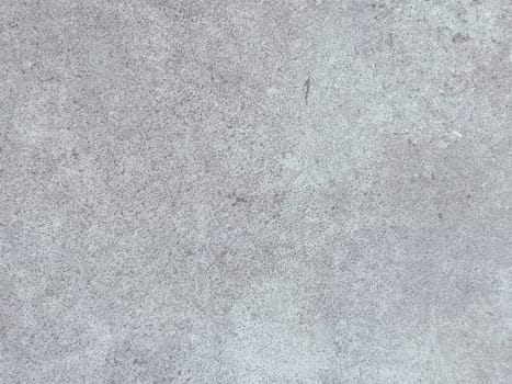 A grey and white wall with a few spots of color. The wall is made of concrete and has a rough texture
