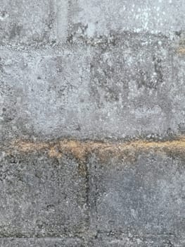 A grey and white wall with a few spots of color. The wall is made of concrete and has a rough texture
