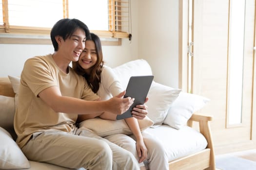 Cheerful young couple relaxing together at home and watching something funny on digital tablet.