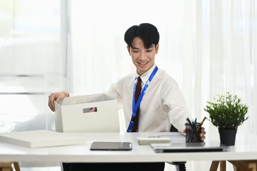 Smiling employee organizing desk supplies in office after getting hired.