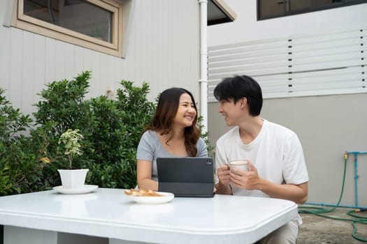 Happy asian couple sharing moments and using digital tablet in garden.