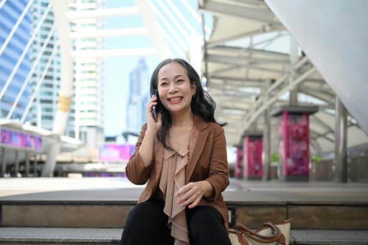 Successful middle aged businesswoman enjoying a phone conversation in modern city.