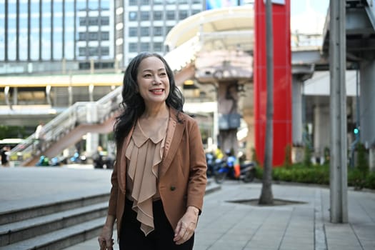 Elegant middle aged businesswoman in stylish suit walking through downtown.