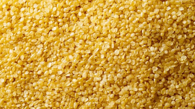 Close-up view of a dense background filled with golden raw bulgur grains, showcasing their texture. ideal for use in culinary presentations, food backdrops, or as a detailed texture for design projects.
