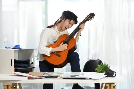 Joyful employee playing guitar during break at the workplace.