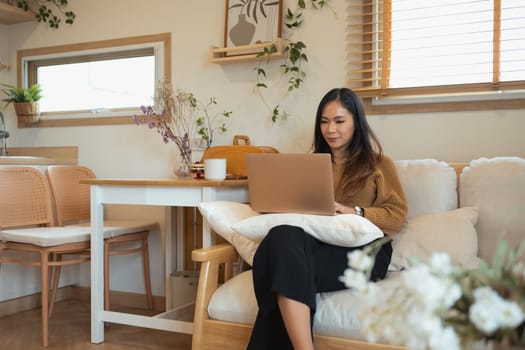 Attractive young woman working with laptop while sitting on couch.