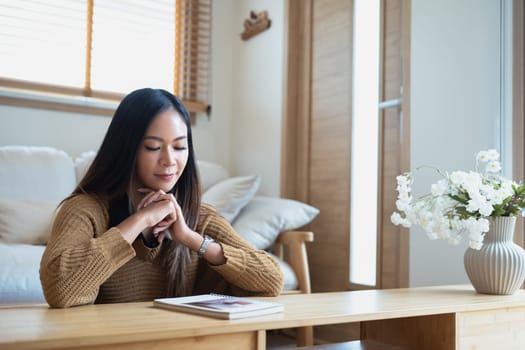 Young adult woman pondering and checking work schedule plan on notebook.