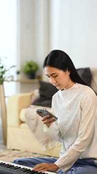 Happy young asian woman checking social media on smartphone at home.