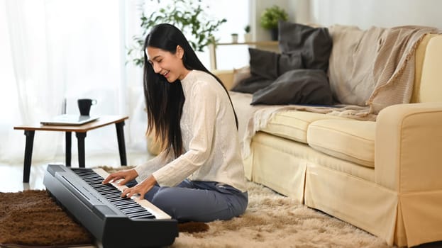 Smiling young woman practicing electric piano in her living room.