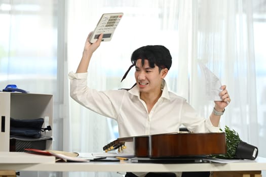 Frustrated male employee smashing calculator in stressful moment.