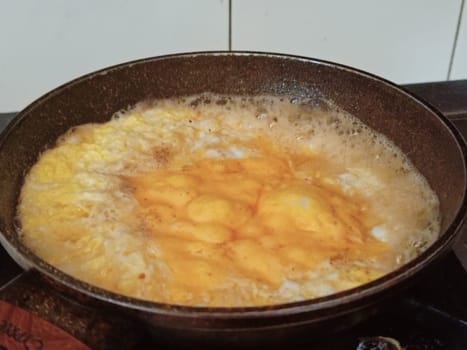 A golden omelette bubbling on a stovetop, showcasing a delicious breakfast in the making. Capturing the essence of home cooking and the warmth of a cozy kitchen.