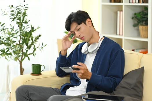 Young asian man playing a video game on smartphone feeling upset after loosing.